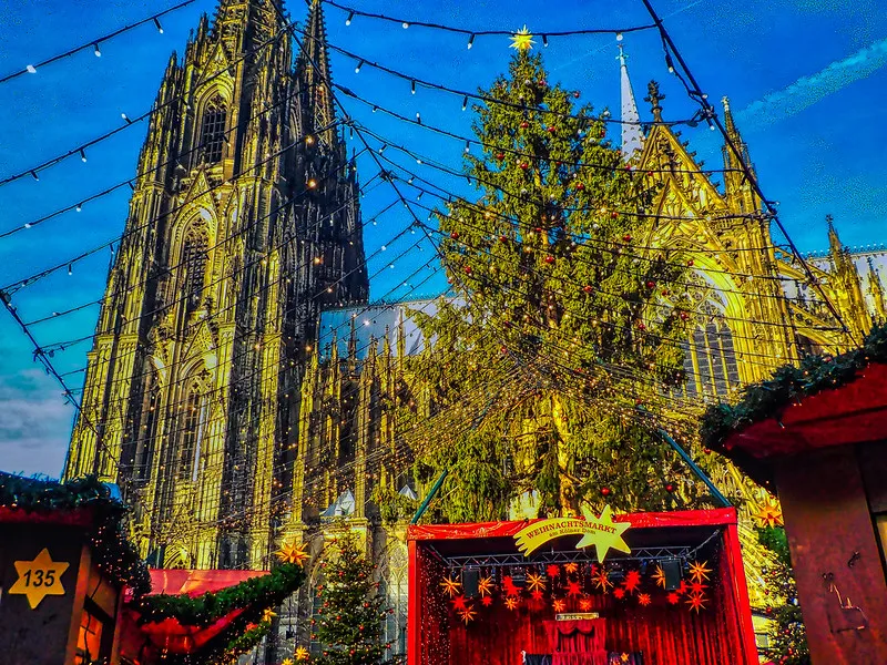 Kerstmarkt aan de Kölner Dom met verlichte kerstbomen en kraampjes in de avond