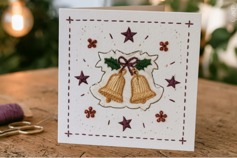 Handgemaakte kerstkaart met een geborduurde klokken-patch, paarse sterretjes en rode knoopjes