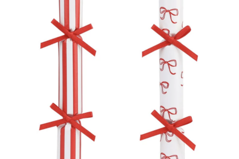 Gedekte kersttafel met rood witte gestreepte knalbonbons met rode strikjes op de borden