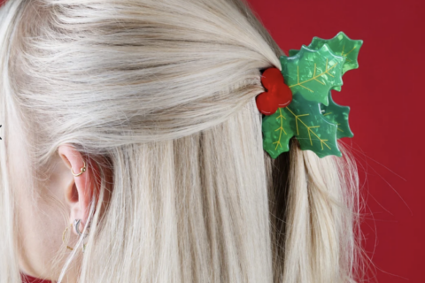 Twee haarklemmen op een marmeren schaaltje een in de vorm van hulst en een in de vorm van een kerstmuts