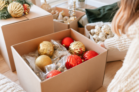 Kartonnen dozen met kerstdecoratie op een zolder waarvan er een openstaat met ingepakte ornamenten