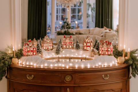 Kerstdorp met verlichte huisjes op een dressoir met watten sneeuw boompjes en een spiegeltje als ijsbaan