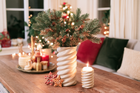 Witte 3D-geprinte spiraalvaas met dennentakken, geprinte sterren en een kandelaar op een houten tafel
