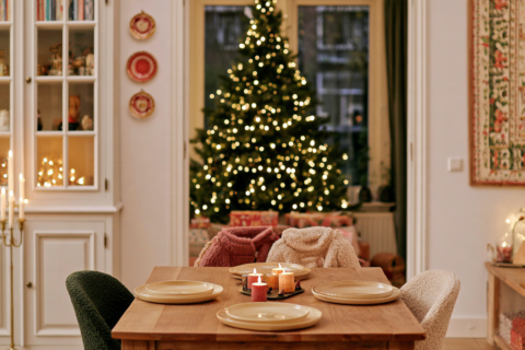 Kersttafel met borden en kaarsen in een rustige woonkamer gedekt voor een klein gezelschap