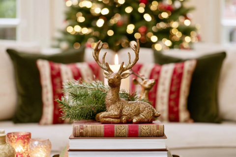 Close up van een matgouden hertenbeeldje met gewei op een stapel boeken bij kaarslicht