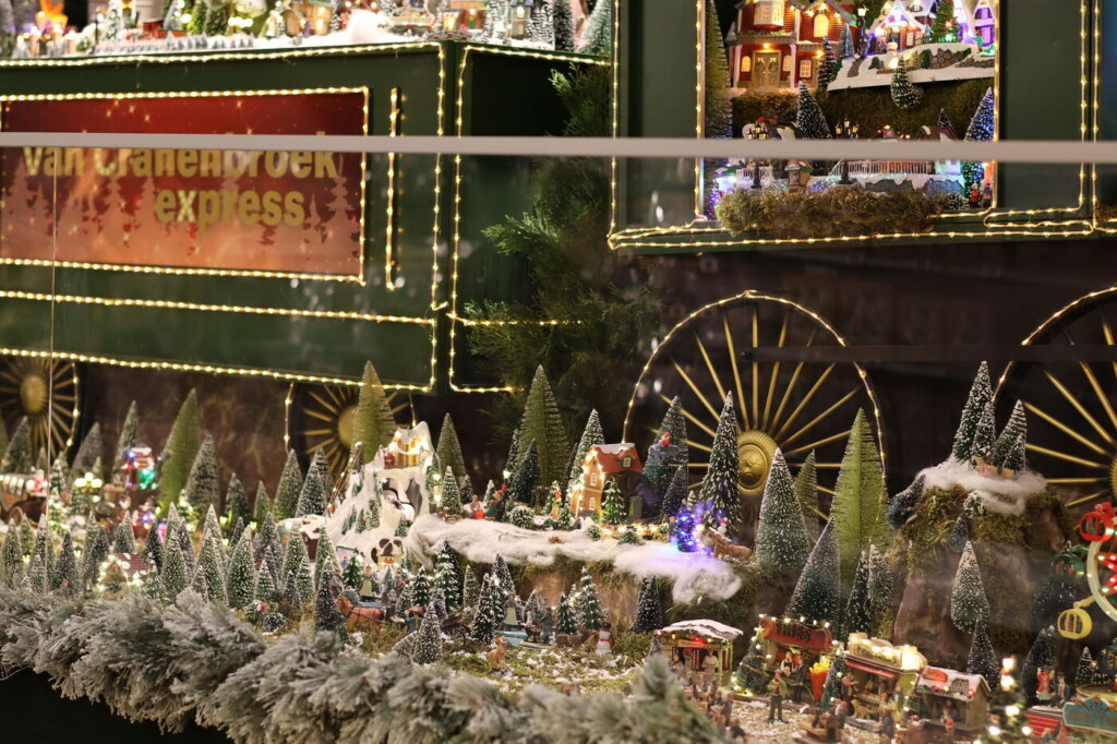 Groot kerstdorp met een groene trein besneeuwde bergen en verlichte huisjes