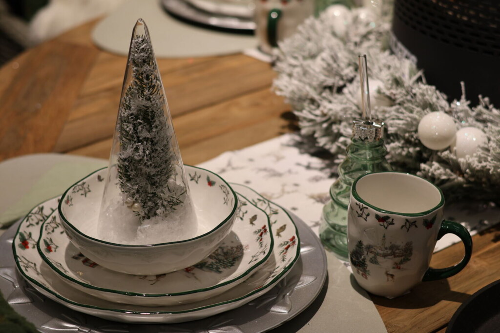Servies met groene rand een beker en een glazen boompje op een winterse tafel